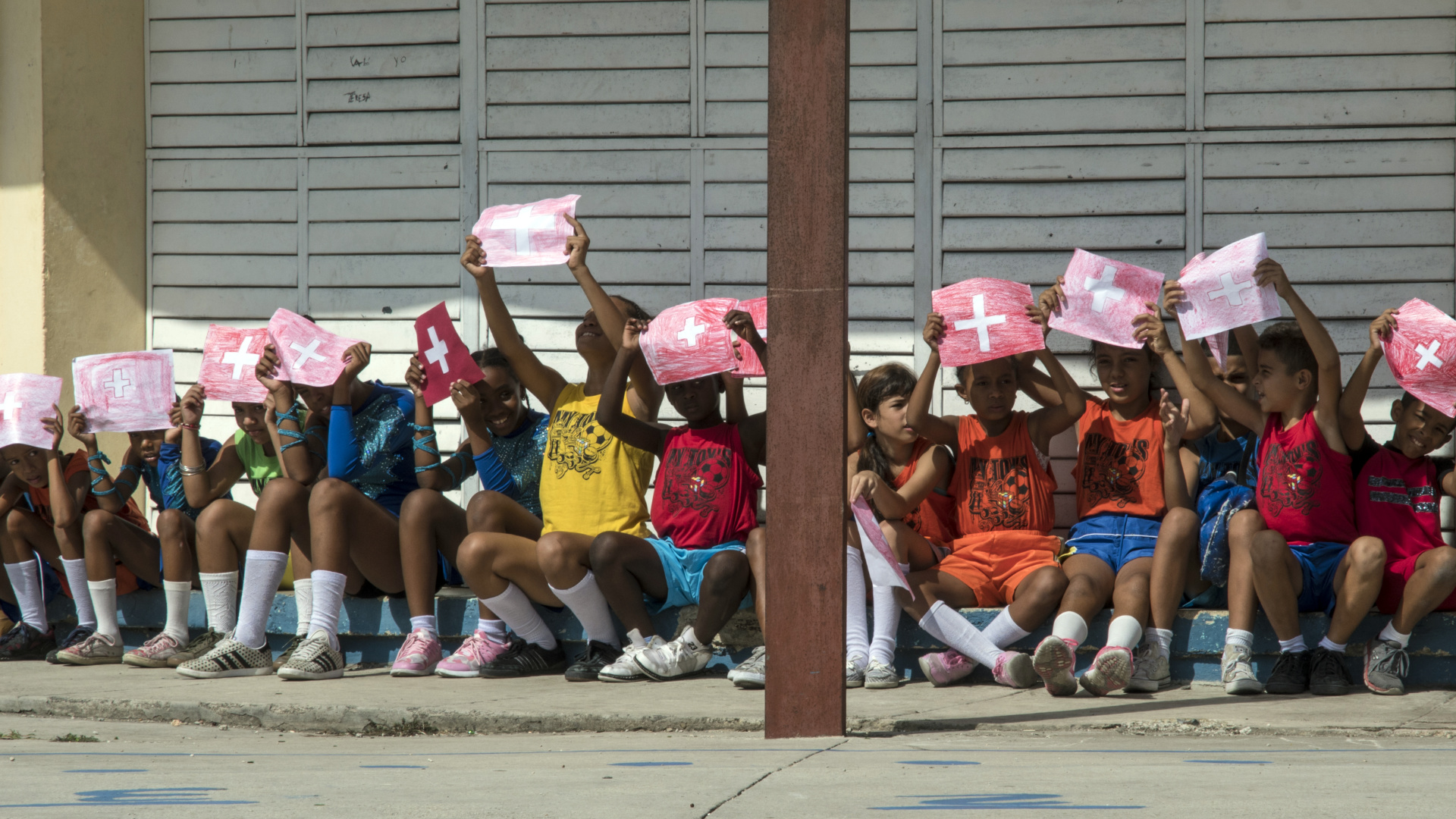 Kinder in einer kubanischen Schule mit Zeichnungen der Schweizer Flagge